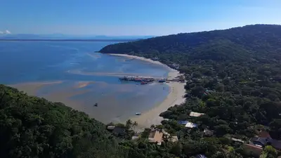 Imagem aérea posicionada da praia do Morro Do Farol de encantadas é direcionada para trapiche com maré baixa